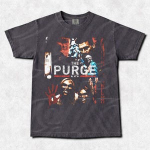 Könnte beinhalten: Dunkelgraues T-Shirt mit einer Grafik aus dem Film "The Purge". Das Design zeigt Bilder von Charakteren und den Filmtitel in Weiß und Rot. Das T-Shirt hat einen Vintage-Look.