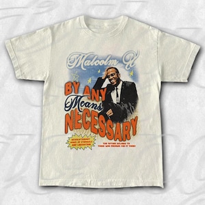 Może przedstawiać: Kremowa koszulka z grafiką Malcolma X w garniturze i krawacie, z napisem "Malcolm X" u góry i "By Any Means Necessary" na dole. Dodatkowy tekst to "Revolutionary Voice of Struggle and Liberation" i "The Future Belongs to Those Who Prepare for it Today."