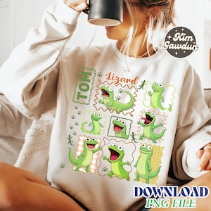 Può includere: Felpa color crema con un design di lucertole dei cartoni animati verdi in varie pose. La parola "Tom" è in una scatola verde e la parola "Lizard" è sopra le lucertole. Il design include piccole illustrazioni di lucertole verdi.