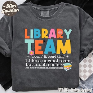 May include: Dark gray sweatshirt with the words "LIBRARY TEAM" in bright orange, blue, pink, and yellow. The text includes a definition and a stack of books. The sweatshirt has a vintage, washed look.