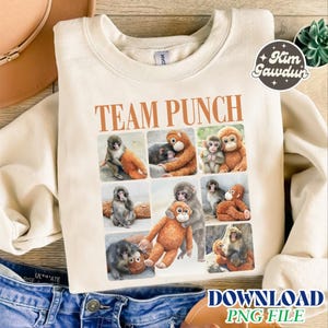 Può includere: Felpa color crema con la scritta "TEAM PUNCH" in marrone. Il design presenta un collage di immagini di scimmie e un peluche di orangutan. Un adesivo rotondo con testo è visibile in alto a destra. Le parole "DOWNLOAD PNG FILE" sono in basso.