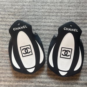 May include: Two black and white shoe tags with the word "CHANEL" and the Chanel logo in white.