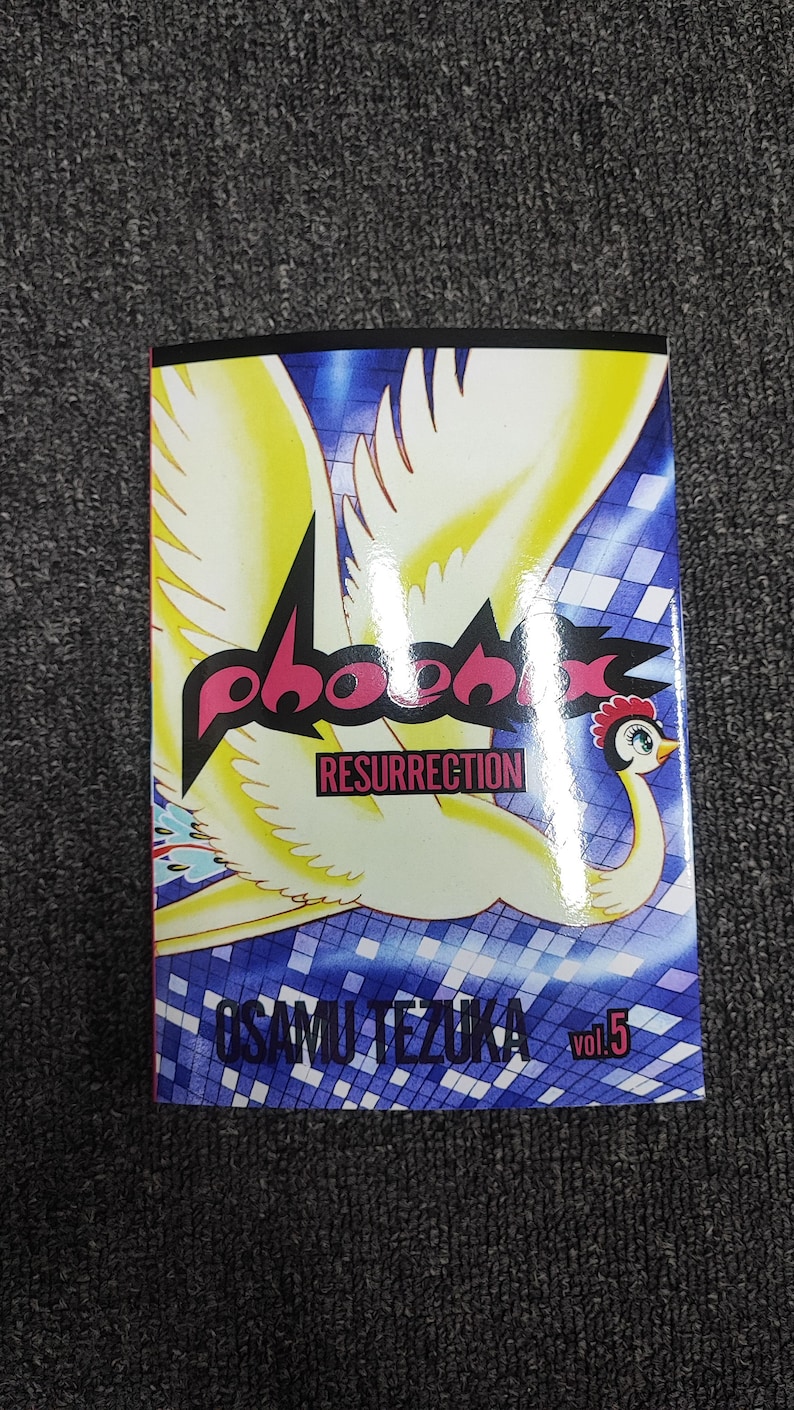 May include: A comic book cover featuring a yellow phoenix with pink and black text that reads "Phoenix Resurrection" and "Osamu Tezuka" with the volume number "Vol. 5".