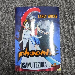 May include: A comic book cover featuring a colorful illustration of a woman and a man in a red and gold helmet. The title "phoenix" is written in orange and yellow letters. The text "EARLY WORKS" and "OSAMU TEZUKA" are also visible. The book is volume 12.