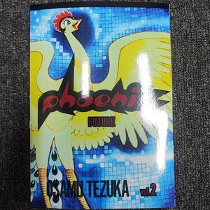 May include: A comic book cover featuring a yellow bird with red and black text that reads "Phoenix Future" and "Osamu Tezuka Vol. 2". The background is a blue and white mosaic pattern.