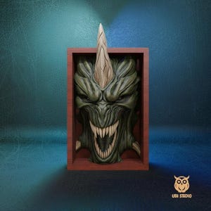 May include: A detailed, green monster face sculpture with a prominent horn, set within a wooden frame. The monster has sharp teeth and a menacing expression. The frame is a reddish-brown color. The UBI STUDIO logo is in the bottom right corner.