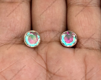 May include: A pair of silver stud earrings with iridescent round gemstones. The gemstones have a faceted cut and reflect a rainbow of colors.