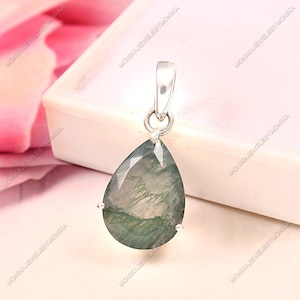 Puede incluir: Un colgante de plata con una piedra preciosa de ágata verde en forma de lágrima con un patrón nublado y veteado.