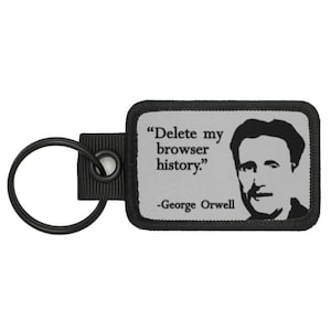 May include: Black and white key chain with a quote from George Orwell: "Delete my browser history." The quote is on a grey background with a black border.