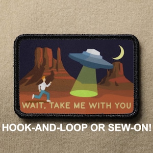 Może przedstawiać: Naszywka haftowana w czerni i bieli przedstawiająca kreskówkowego mężczyznę uciekającego przed latającym spodkiem. Naszywka ma ciemnoniebieskie tło z czerwonymi i pomarańczowymi górami pustynnymi. Na naszywce nadrukowany jest tekst "WAIT, TAKE ME WITH YOU". Naszywka jest oznaczona jako "HOOK-AND-LOOP OR SEW-ON!"