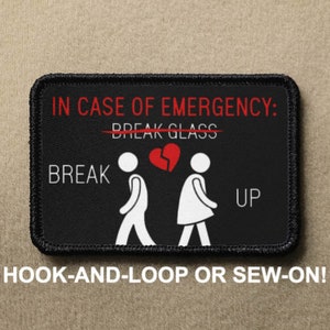 May include: Black and white patch with the text "IN CASE OF EMERGENCY: BREAK GLASS" with a line through the word "BREAK".  The text "BREAK" is below the line and the text "UP" is above the line.  Two stick figures are walking away from each other with a broken heart between them.  The text "HOOK-AND-LOOP OR SEW-ON!" is below the patch.