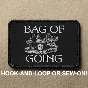 May include: Black and white embroidered patch with the text "BAG OF GOING" and a black and white illustration of a horse-drawn wagon with people inside. The patch has a black border and is labeled "HOOK-AND-LOOP OR SEW-ON!"