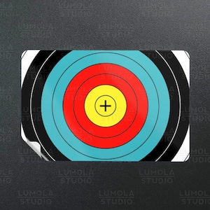May include: A circular archery target with black, white, blue, red, and yellow concentric rings. The center of the target has a yellow circle with a red cross.