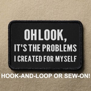 Könnte beinhalten: Schwarzer Patch mit weißem Text, der "OHLOOK, IT'S THE PROBLEMS I CREATED FOR MYSELF" lautet. Der Patch ist für Klettverschluss oder zum Annähen geeignet.