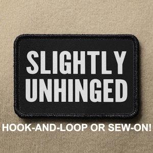 May include: Black rectangular patch with the words "SLIGHTLY UNHINGED" in bold white letters. The patch has a black border and the text "HOOK-AND-LOOP OR SEW-ON!" in white letters below the main text.
