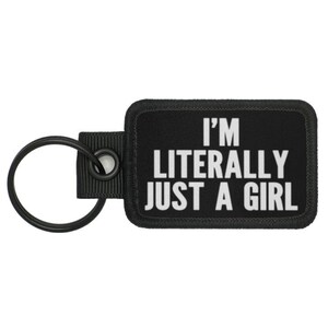 Puede incluir: Llavero negro con una etiqueta blanca que dice "Soy literalmente solo una chica."
