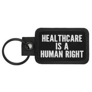 May include: Black key chain with a black rectangular tag that reads "Healthcare is a Human Right" in white text.