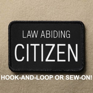 Op de afbeelding: Zwarte patch met witte tekst die "LAW ABIDING CITIZEN" luidt. De patch is geschikt voor klittenband of naaien.