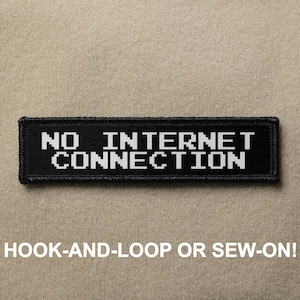 Peut inclure: Patch noir avec du texte blanc qui dit "NO INTERNET CONNECTION". Le patch est conçu pour être cousu ou fixé avec du velcro.
