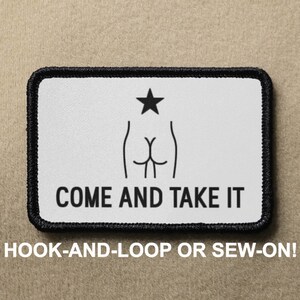 May include: White patch with black outline, featuring a stylized image of a rear end with a star above it. The text "COME AND TAKE IT" is printed below the image. The patch is designed for hook-and-loop or sew-on attachment.