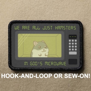 以下が含まれることがあります： 「WE ARE ALL JUST HAMSTERS IN GOD'S MICROWAVE」の文字が入った黒い長方形のパッチ。電子レンジの中に漫画のハムスターが描かれています。パッチの下部には「HOOK-AND-LOOP OR SEW-ON！」と書かれています。