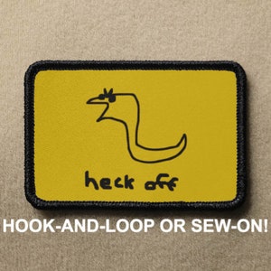 May include: Yellow embroidered patch with a black line drawing of a bird with the text "heck off" on a yellow background. The patch has a black border and is designed to be sewn or attached with hook and loop.