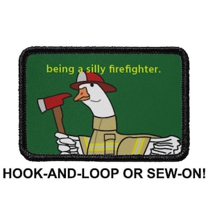 Peut inclure: Un écusson brodé vert et noir avec une oie blanche portant un casque de pompier rouge et tenant une hache. Le texte "being a silly firefighter." est écrit en jaune sur l'écusson.
