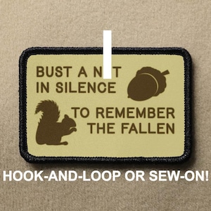 Könnte beinhalten: Ein beigefarbener Patch mit schwarzen Nähten an den Rändern. Der Patch zeigt ein Eichhörnchen, eine Eichel und den Text "Bust a nut in silence to remember the fallen". Der Text ist in Braun. Der Patch ist zum Anbringen mit Klettverschluss oder zum Annähen geeignet.