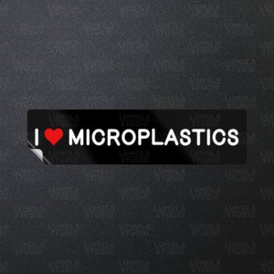 May include: A black and white sticker with a red heart and the text "I ♥ MICROPLASTICS" with the words "LUMOLA STUDIO" repeated on the top and bottom of the sticker.