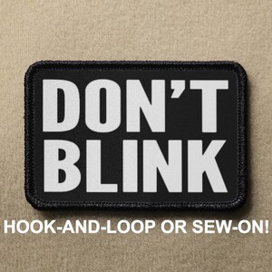 May include: Black patch with white text that reads "DON'T BLINK". The patch is for hook-and-loop or sew-on attachment.