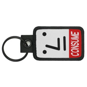 May include: Black and white key chain with a white rectangle with a black face and the word "CONSUME" in red text on a red rectangle.
