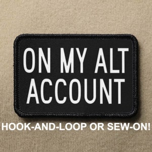 May include: Black patch with white text that reads "ON MY ALT ACCOUNT". The patch has a black border and is designed to be attached with hook-and-loop or sewn on.