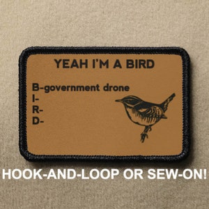 May include: A brown patch with black stitching features a black and white illustration of a bird with the text "YEAH I'M A BIRD" and "B-government drone" with the letters "BIRD" listed vertically. The patch has the text "HOOK-AND-LOOP OR SEW-ON!" below it.