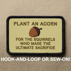 May include: A brown and black embroidered patch with the text "PLANT AN ACORN FOR THE SQUIRRELS WHO MADE THE ULTIMATE SACRIFICE". The patch features a cartoon acorn with a brown cap and a light brown body. The patch is surrounded by a black border and has a hook-and-loop or sew-on option.