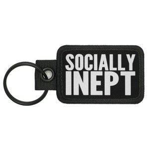 May include: Black key chain with a black rectangular patch that says "SOCIALLY INEPPT" in white letters.