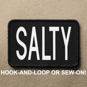 May include: Black patch with white text that reads "SALTY". The patch is for hook-and-loop or sew-on attachment.