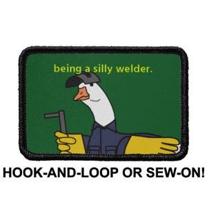 Può includere: Una toppa verde e nera con un'oca di cartone animato che indossa un casco da saldatore e tiene una torcia da saldatore. Il testo "being a silly welder." è sopra l'oca. La toppa ha un retro in velcro o da cucire.