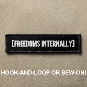 Puede incluir: Parche negro con texto blanco que dice "[FREEDOMS INTERNALLY]". El parche está diseñado para ser fijado con velcro o cosido.