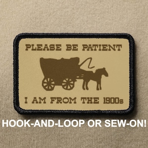 May include: A tan and brown embroidered patch with black stitching. The patch features a silhouette of a horse-drawn wagon with the text "PLEASE BE PATIENT I AM FROM THE 1900s". The patch is designed to be attached with hook-and-loop or sewn on.