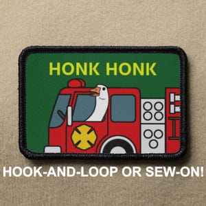 May include: A red fire truck with a goose driving it. The truck has a yellow cross on the side and the words "Honk Honk" on the front. The patch is black with a white border and says "Hook-and-Loop or Sew-On!" at the bottom.