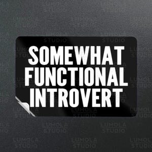May include: A black rectangular sticker with the words "SOMEWHAT FUNCTIONAL INTROVERT" in bold white capital letters. The sticker has a peel-off corner and the words "LUMOLA STUDIO" are printed around the edges.