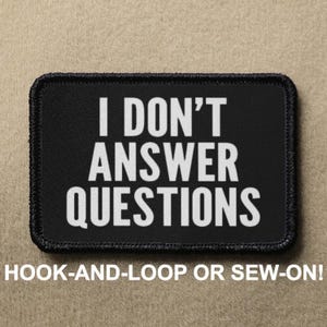 May include: Black patch with white text that reads "I DON'T ANSWER QUESTIONS". The patch is sewn with black thread and has a hook-and-loop or sew-on option.