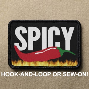 Może przedstawiać: Czarna łatka z białym tekstem "SPICY" i czerwoną papryczką chili z zielonym ogonkiem na płomieniach. Łatka jest do przyklejania na rzep lub do przyszycia.