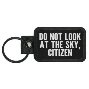 May include: Black key chain with a white rectangular tag that reads "Do Not Look At The Sky, Citizen".