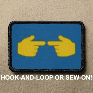 May include: A blue and black embroidered patch with two yellow pointing hands. The text "HOOK-AND-LOOP OR SEW-ON!" is printed below the patch.