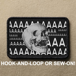 May include: Black and white embroidered patch with a skull screaming and the text "AAAAAAA" repeated in a pattern.