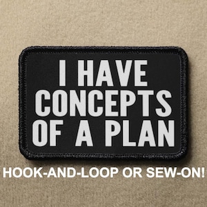 Op de afbeelding: Zwarte patch met witte tekst die "IK HEB CONCEPTEN VAN EEN PLAN" luidt. De patch heeft een zwarte rand en is ontworpen om met klittenband te worden bevestigd of aangehecht te worden.