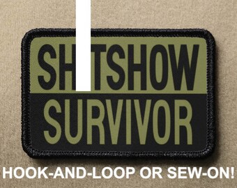 May include: Black and green embroidered patch with the text "SHITSHOW SURVIVOR" in white lettering. The patch has a black border and is designed to be attached with hook-and-loop or sewn on.