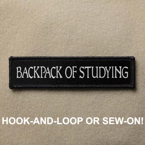 Könnte beinhalten: Schwarz-weiß gestickter Aufnäher mit dem Text "BACKPACK OF STUDYING" auf schwarzem Hintergrund. Der Aufnäher ist zum Anbringen mit Klettverschluss oder zum Annähen gedacht.