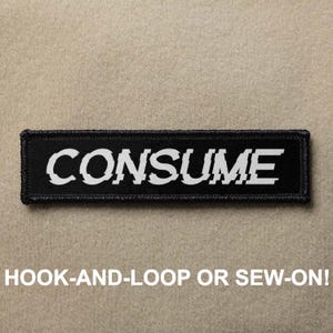 May include: Black patch with white text that reads "CONSUME". The patch is designed to be sewn or attached with hook-and-loop.